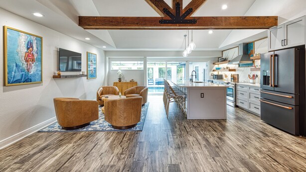 Una cocina amplia con electrodomésticos modernos, vigas de madera y un comedor con sillas de cuero.