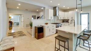 Una cocina moderna con armarios blancos, una isla central y taburetes de bar.
