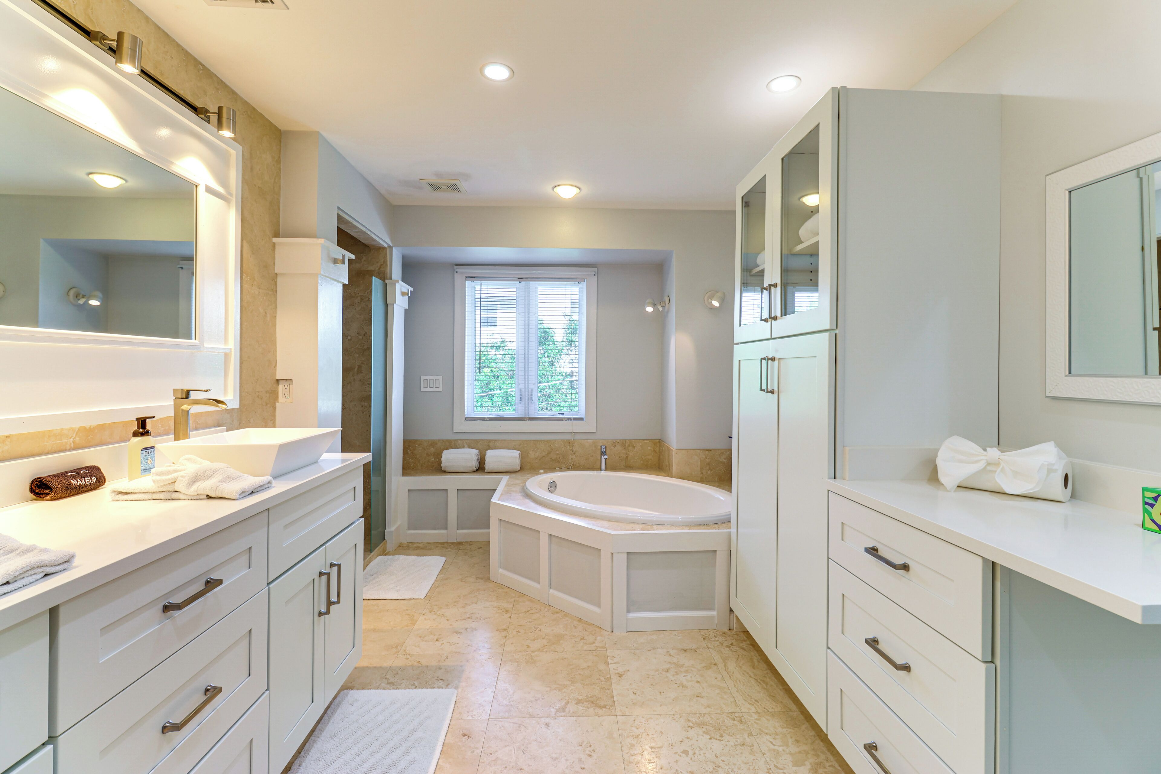 A modern bathroom with a large mirror, a bathtub, and a vanity with a sink.