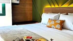 Una habitación de hotel con una cama, una bandeja con alimentos para el desayuno y un microondas en la pared.