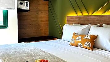 Quarto de hotel com cama, bandeja de café da manhã e micro-ondas na parede.