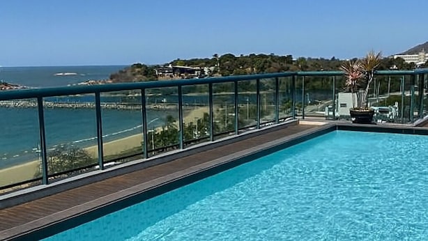 Una piscina con vista despejada al océano y una colina distante.