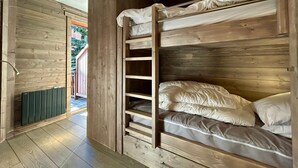 Une chambre avec un lit superposé, des murs en bois et un radiateur.