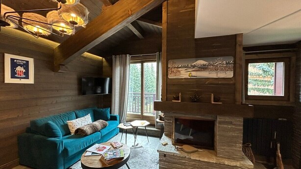 Un salon chaleureux avec un canapé bleu, une cheminée et un téléviseur fixé au mur.