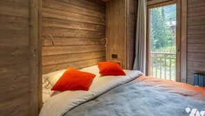 Une chambre dans une cabane en bois, avec un lit, deux oreillers et une vue sur l’extérieur.