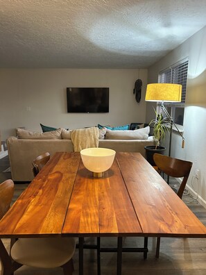 A dining area with a wooden table, chairs, a bowl, and a lamp.