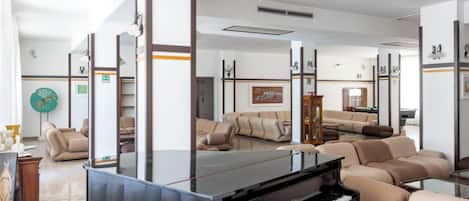 A spacious room with a grand piano, comfortable seating, and a large mirror.