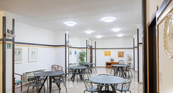 Une salle de conférence équipée de tables et de chaises, avec une plante et des œuvres d’art accrochées aux murs.