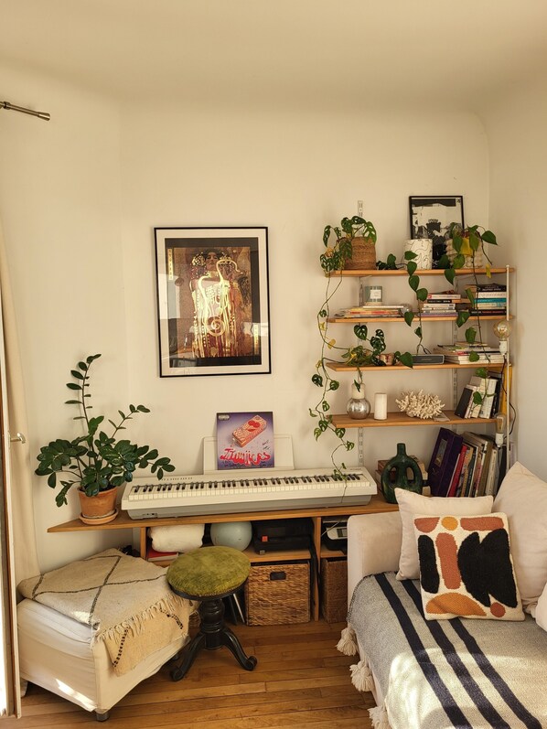 Ein gemütliches Zimmer mit einem Bett, einem Schreibtisch inklusive Tastatur, einem Bücherregal und einigen Pflanzen.