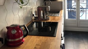 A modern kitchen with a coffee maker, kettle, and a plant on the counter. - Bright apartment with balcony (Clichy)