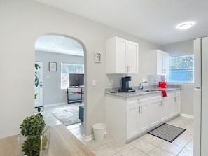 A modern kitchen with white cabinets, a coffee maker, and a red toaster.