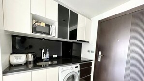 A compact kitchen with a microwave, toaster, and washing machine.