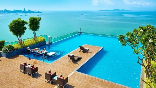 A rooftop infinity pool with lounge chairs and a view of the ocean.