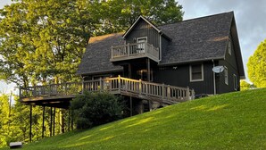 Ein zweistöckiges Haus mit Balkon, umgeben von üppiger Vegetation und Bäumen.