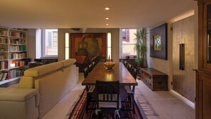 A dining area with a long wooden table, cushioned seating, a bookshelf, and a large abstract painting. - "Elegant 2 Level Duplex 2 Baths & Bikes -Trastevere" (Roma)