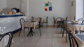 A restaurant with tables and chairs, a counter, and a wall with a geometric painting. -  Hotiday La Spezia Centrale (La Spezia)