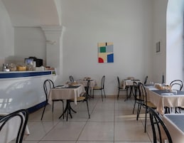 Un restaurante con mesas, sillas, una barra y una pared con un cuadro de motivos geométricos.