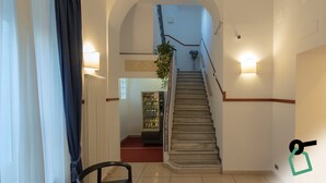 Eine Treppe mit Handlauf, ein Getränkeautomat und ein Blumentopf.