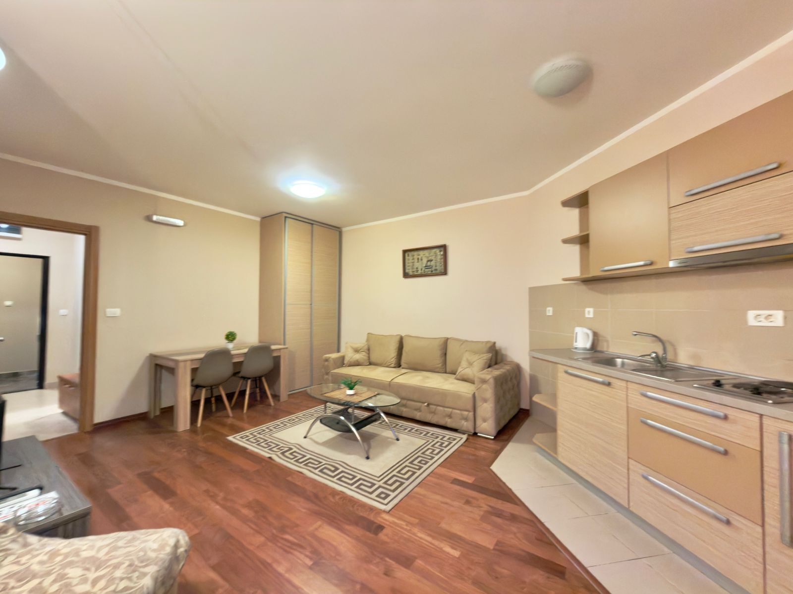 A compact living space with a kitchenette, a sofa, a coffee table, and a dining area.