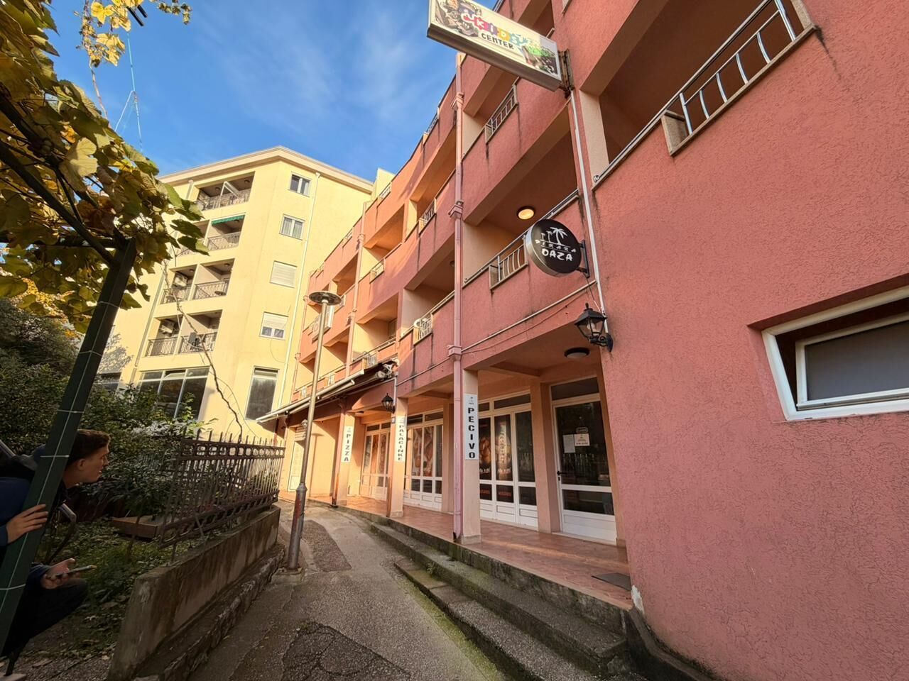 A multi-story building with balconies, a sign for 'Daza', and a small window.
