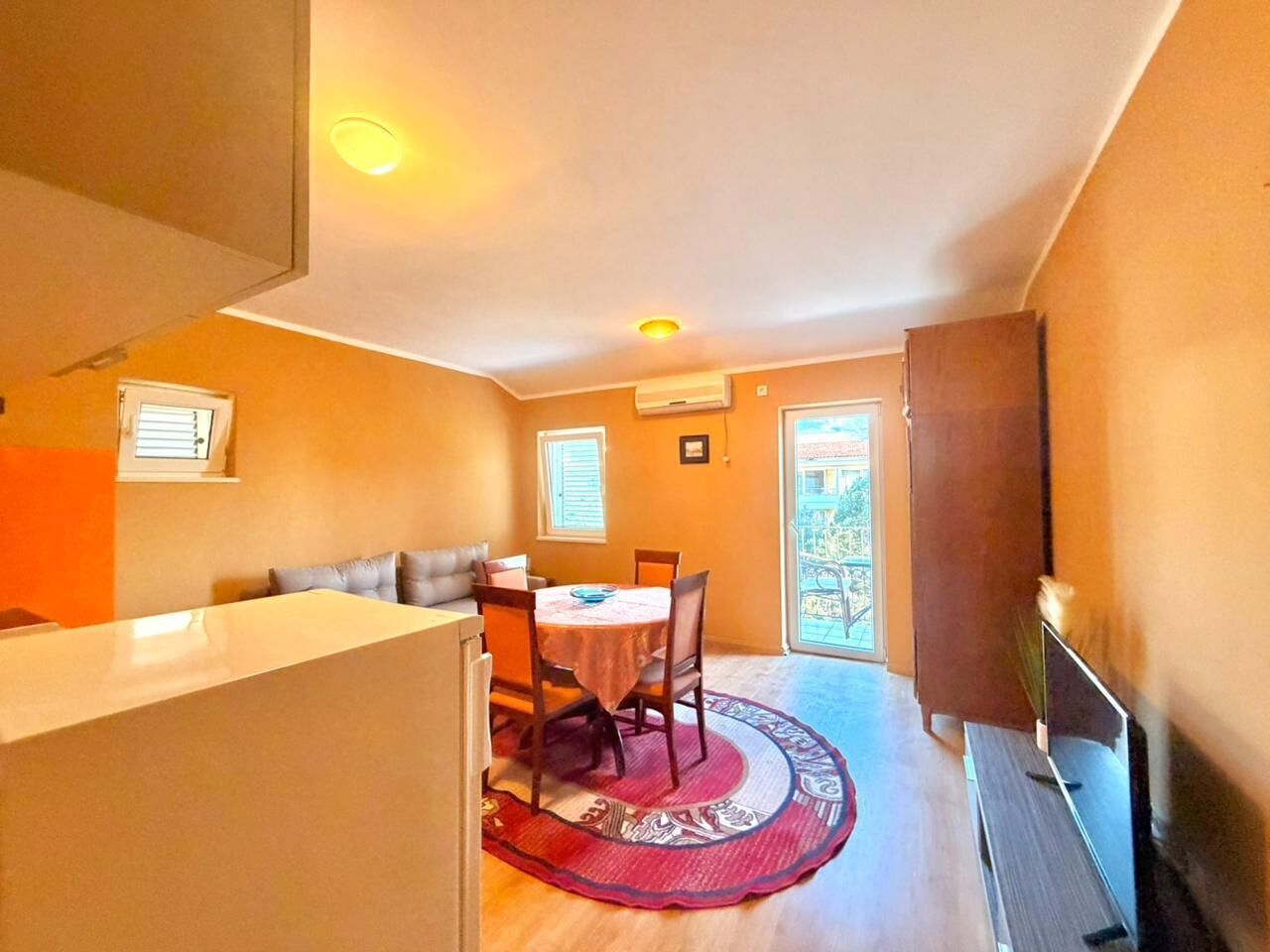 Un espacio habitable compacto con comedor, kitchenette y balcón.