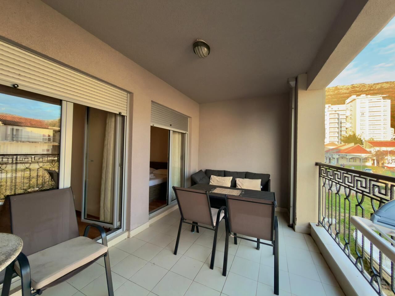 A balcony with a table and chairs, a sliding door, and a view of buildings.