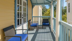 Eine überdachte Veranda mit zwei Korbstühlen und einem Tisch, gestaltet in Blau und Weiß.