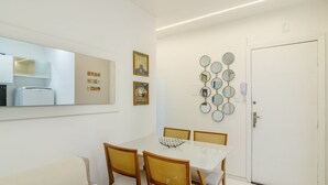 A dining area with a white table, four chairs, a sofa, a refrigerator, and a door. - Apt With A/C 350m From the Beach in BC Esf0203 (Balneário Camboriú)