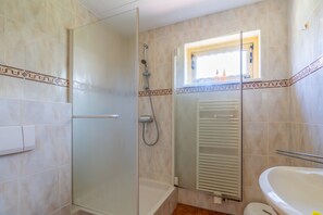 Ein Badezimmer mit Duschkabine aus Glas, einer Badewanne und einem Fenster mit Ausblick.