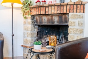 A fireplace with a brick surround, a potted plant, a wicker basket, and a lamp.
