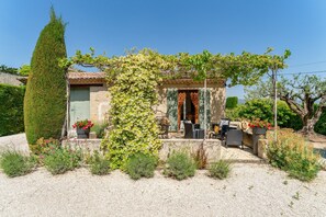 A house with a garden, a pergola, and outdoor furniture.