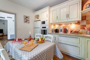 A kitchen with white cabinets, a dining table with a polka dot tablecloth, and various kitchen appliances.