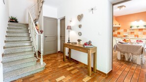 Eine Treppe führt zu einem Raum mit Essbereich, einem Tisch und Stühlen sowie einer Wand mit Dekoration.