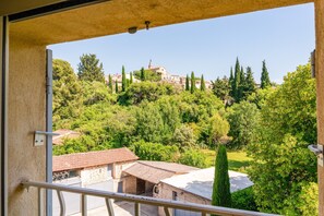 Ein Balkon mit Blick auf eine Hügelkuppe mit Gebäuden und Bäumen.