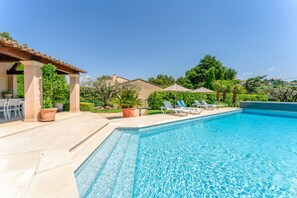 Ein Swimmingpool mit Liegestühlen, einer Pergola und Topfpflanzen.