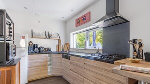 Una cocina moderna con armarios de madera, horno empotrado y ventana que deja entrar luz natural.