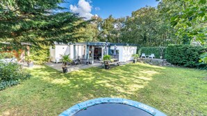 Una casa con un patio trasero pequeño, un trampolín y plantas en macetas.