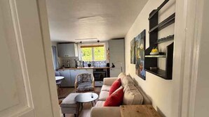 Ein kompakter Wohnbereich mit Küchenzeile, einer Couch, einem kleinen Tisch und einer Holzkiste.