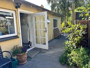 A house with a garden, a door, a bench, and a potted plant.
