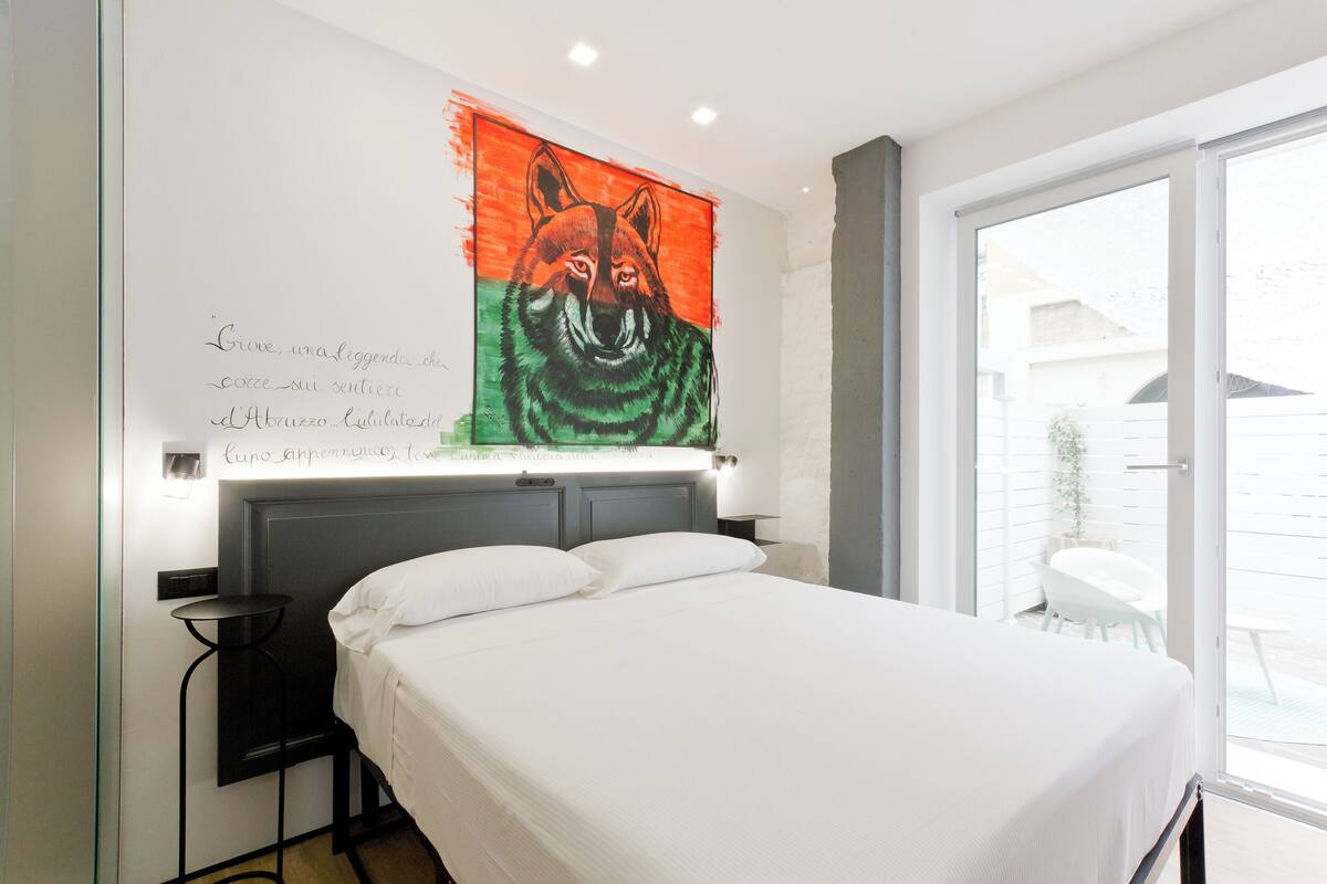 Ein Schlafzimmer mit einem Bett, einem an der Wand hängenden Bild eines Fuchses und einem Fenster mit Blick nach draußen.