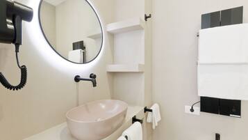 A modern bathroom with a round mirror, a beige sink, and a towel rack.