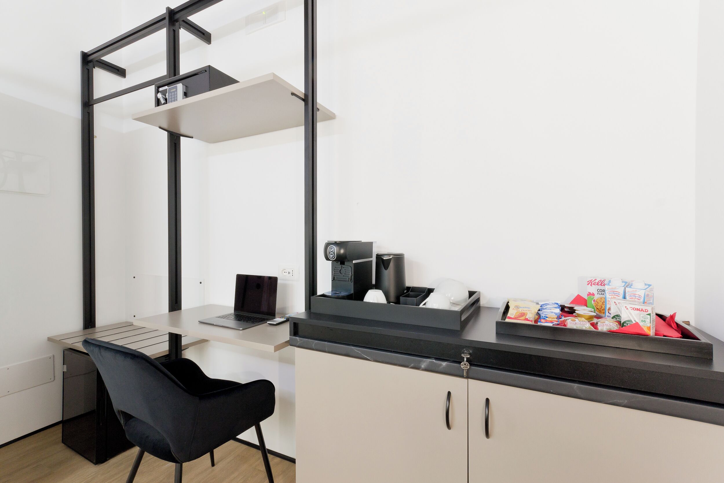 A modern office space with a desk, chair, coffee machine, and a small shelf with a keyboard.
