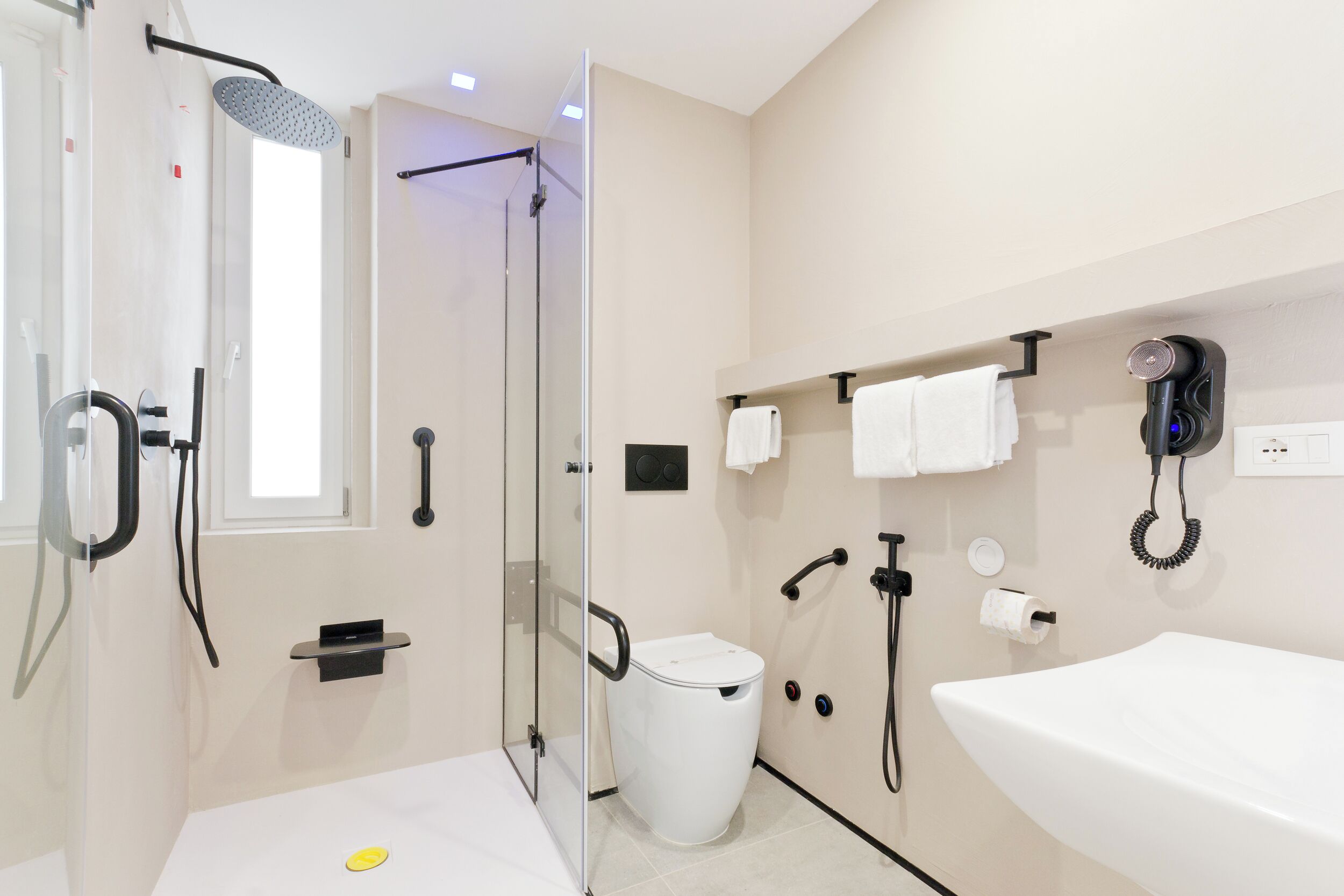 Une salle de bain moderne avec une douche à parois de verre, un lavabo blanc et des toilettes.