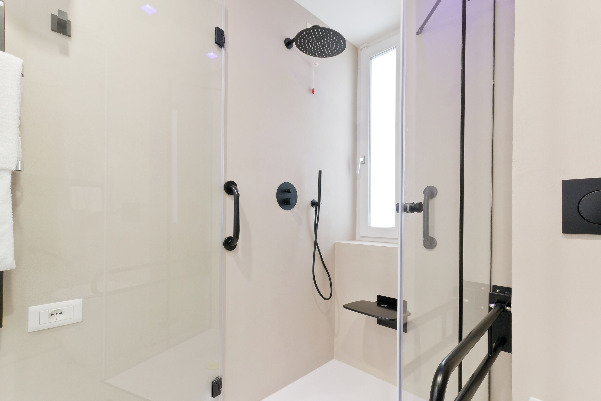 Un baño moderno con cabina de ducha de vidrio, cabezal de ducha manual y estante integrado.