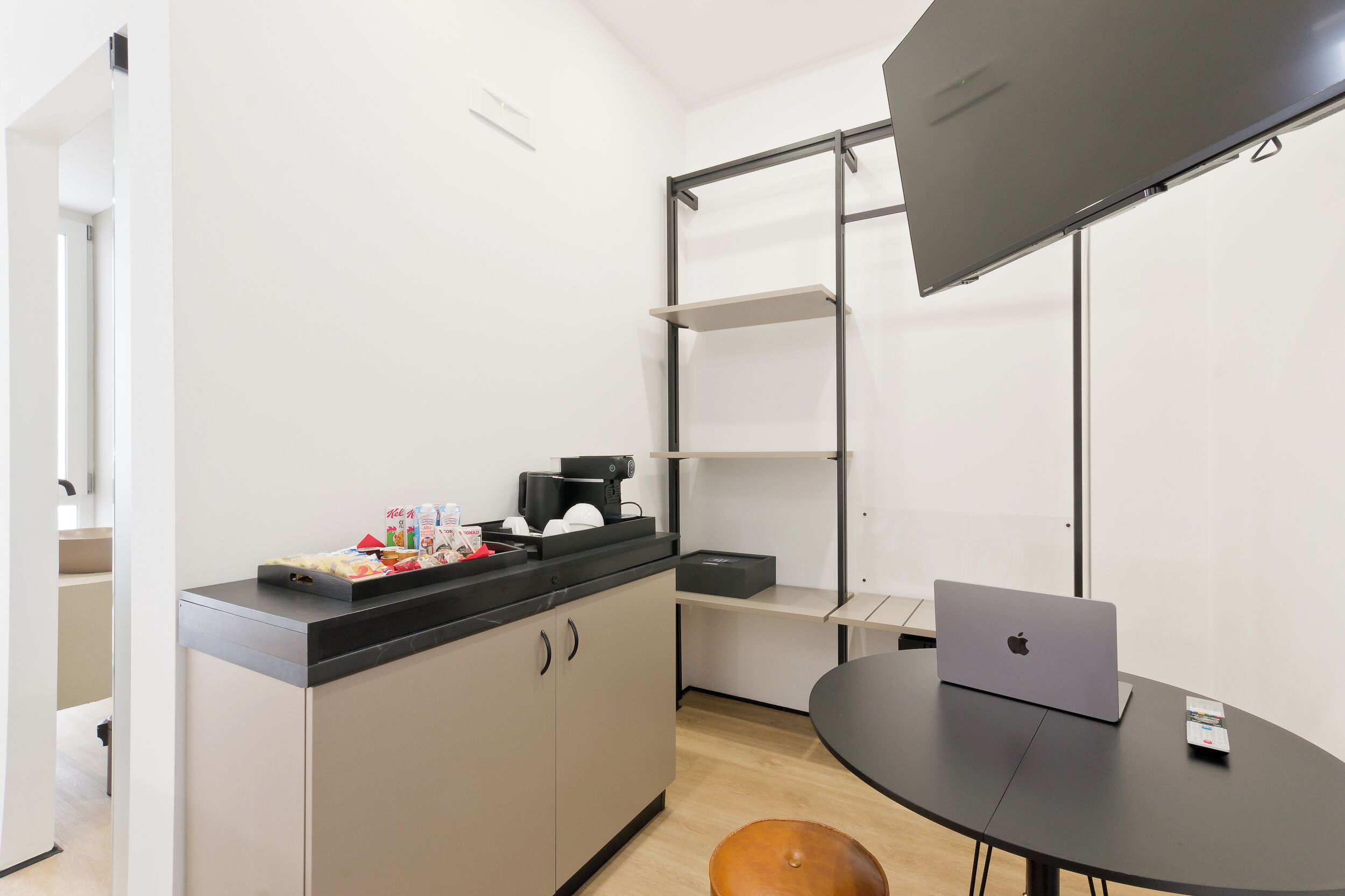 A modern kitchen with a black countertop, a coffee machine, and a laptop on a table.