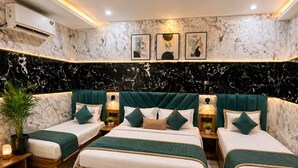 A hotel room with three beds, marble walls, and a 'bath' mat. - HOTEL JS INN (Ayodhya)