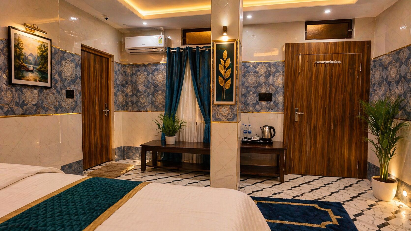 A hotel room with a bed, a desk, a potted plant, a wall-mounted air conditioner, and a decorative painting.