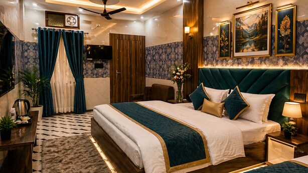 A hotel room with a large bed, a ceiling fan, a TV, and a bathroom with a shower and toilet. - HOTEL JS INN (Ayodhya)