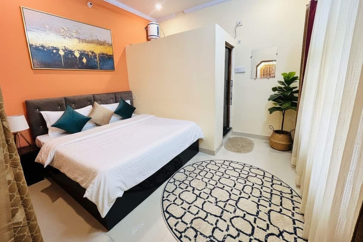 A bedroom with a bed, a painting, a potted plant, and a round rug.