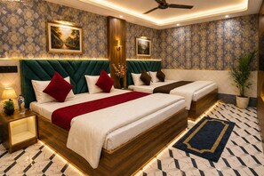 A hotel room with a large bed, two bedside tables, a ceiling fan, and patterned wallpaper. - HOTEL JS INN (Ayodhya)